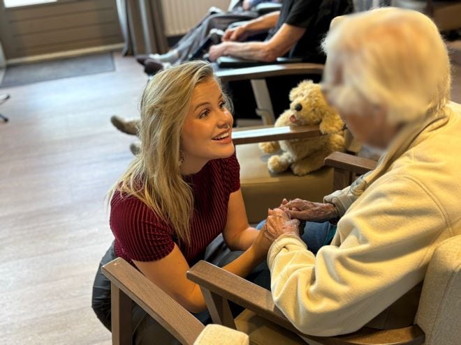 NextGen: Zingen met zorg Yvon Kanters gehurkt tegenover oudere dame met dementie